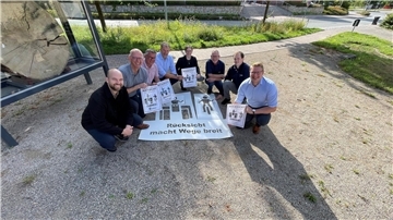 8 lächelnde Leute sitzen in der Hocke mit Plakaten „Rücksicht macht Wege breit“
