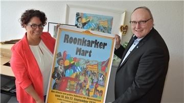 Sie zeigen voller Vorfreude das Plakat für den 890. Roonkarker Mart: Marktmeisterin Christiane Hagen und Bürgermeister Harald Stindt.