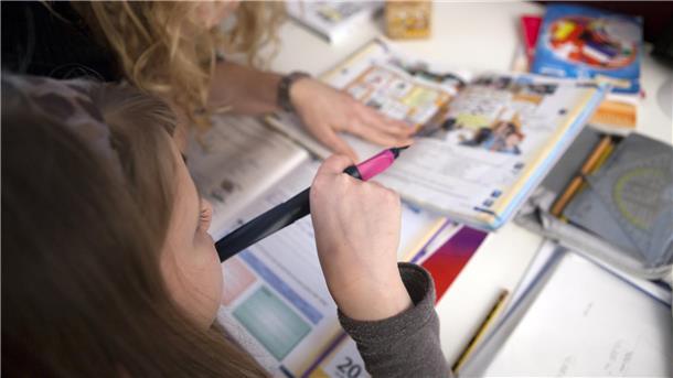 Kind sitzt über einem Schulheft