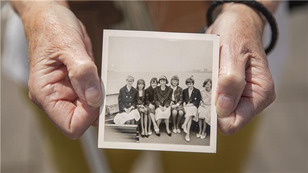 Diese Fahrt mit der „Oceana“ hat die Mädchen zusammengeschweißt Hände halten ein historisches Bild, das eine Gruppe von Frauen an Deck der Oceana zeigt.
