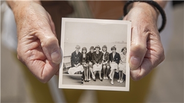 Hände halten ein historisches Bild, das eine Gruppe von Frauen an Deck der Oceana zeigt.