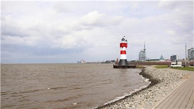 Ein rot-weißer Leuchtturm vor der Skyline Bremerhavens.