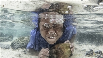 So spielt man in Samoa Wasserball: Ein Mädchen taucht auf der Insel Upolu mit einer Kokosnuss unter.
