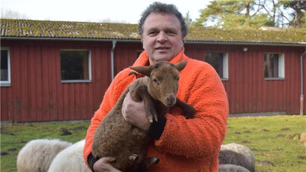Sönke Hofmann hält auf dem Gelände der Dreptefarm ein Lamm im Arm
