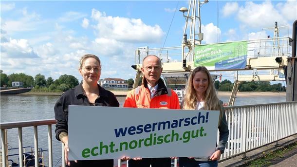 Sophia Wolfram (Gemeinde Ovelgönne, Mitglied der Steuerungsgruppe Standortmarketing), Andreas Bettray (Geschäftsführer der Fähren Bremen-Stedingen) und Isa Grube (Wirtschaftsförderung Wesermarsch) präsentieren den Slogan der Kampagne.