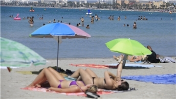 Urlauber liegen unter Sonnenschirmen am Strand