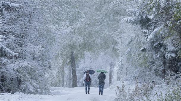 Spätes Winterwetter in Teilen von Deutschland Spaziergänger laufen über einen verschneiten Wanderweg im Taunus.