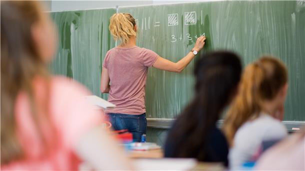 Eine junge Lehrerin schreibt an eine Schultafel