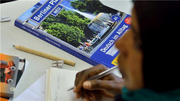Das Lehrbuch "Deutsch im Alltag" liegt in einem Deutschkurs für Flüchtlinge vor einer jungen Frau auf der Schulbank.