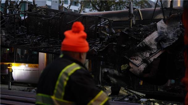 Spuren der Ausschreitungen in Dublin. Ein Arbeiter steht vor einer ausgebrannten Straßenbahn.