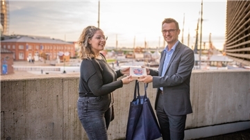 Stadtrat Michael Frost begrüßt die Spanierin Cecilia Hernandéz Garcia in Bremerhaven. Die Begrüßungstasche für die Kita-Fachkraft enthält unter anderem eine Fahrt mit dem Hafenbus. Foto: Hartmann