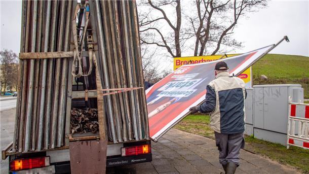 Ein Mann stellt ein Großplakat auf