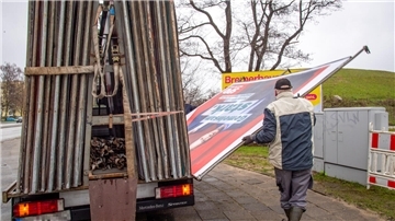 Ein Mann stellt ein Großplakat auf