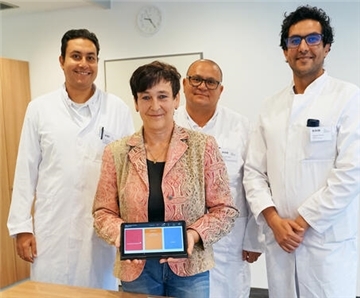 Drei Männer und eine Frau stehen nebeneinander und präsentieren eine App zur mobilen Überwachung von Herzpatienten. 