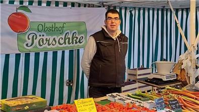 Mann hinter einem Wochenmarktstand mit Obst und Gemüse.