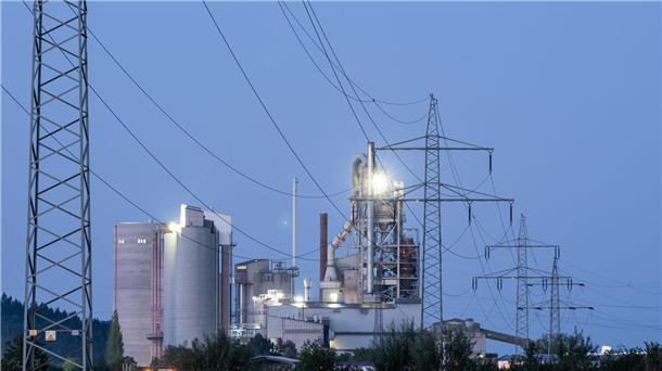 Strompreispaket: Wie viel Entlastung ist wirklich geplant? Strommasten stehen im Morgenlicht vor einem Zementwerk: Die Bundesregierung will den Strompreis für die Wirtschaft durch eine Steuerreform drücken senken.