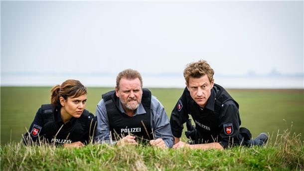 Zwischen Idylle und Cannabis: „Friesland - Bis aufs Blut“ Süher Özlügül (Sophie Dal, l.), Kriminalhauptkommissar Brockhorst (Felix Vörtler, M.) und Henk Cassens (Maxim Mehmet, r.) beobachten eine Situation vom Deich aus.