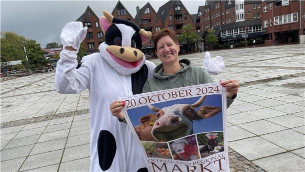 Frau mit einem Plakat neben eine Frau in einem Ochsenkostüm