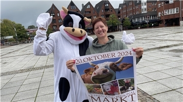 Frau mit einem Plakat neben eine Frau in einem Ochsenkostüm