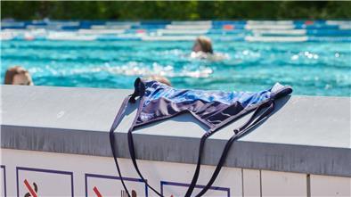 Symbolbild: Ein Badeanzug liegt auf einer Mauer im Freibad.