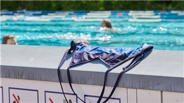 Symbolbild: Ein Badeanzug liegt auf einer Mauer im Freibad.