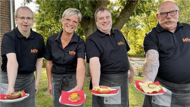 Drei Männer und eine Frau halten belegte Brötchen in die Kamera.