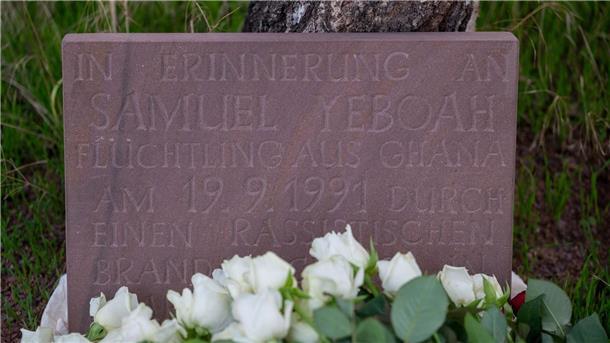 Brandanschlag Saarlouis: Zweiter Verdächtiger festgenommen Teilnehmer der Gedenkkundgebung für den 1991 bei einem Brandanschlag getöteten ghanaischen Asylbewerber Samuel Yeboah haben an einem Gedenkstein Blumen abgelegt.