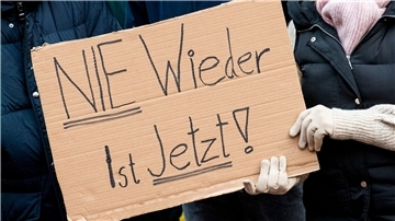 Teilnehmer einer Demonstration gegen Rechtsextremismus unter dem Motto „Nie wieder ist jetzt“ halten ein Schild.