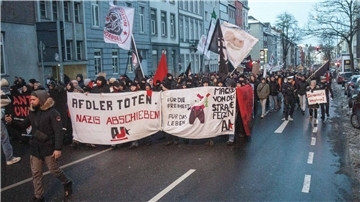 Teilnehmer einer Demonstration mit einem Plakat und der Aufschrift „AfDler töten. Nazis abschieben!“.