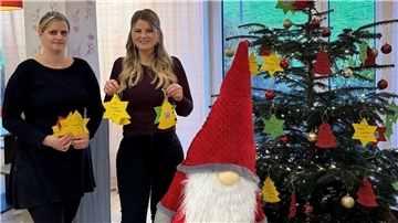 Zwei Frauen neben einem Weihnachtsbaum.