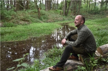 Das Foto zeigt Thorben Rievesehl an einem Teich im Wald sitzend.  