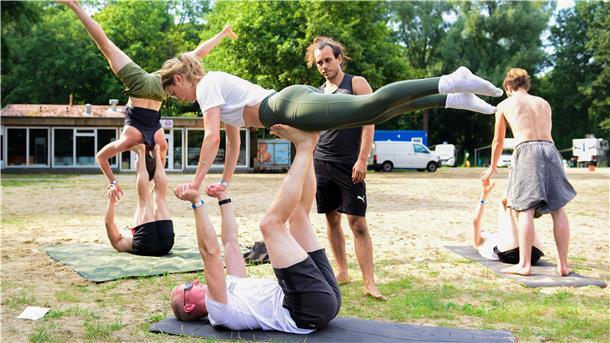 Tobias und Caro lassen sich beim „Acro Yoga“ von Kursleiter Yannick einige Kniffe zeigen.