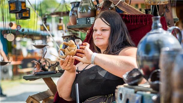 Eine Frau hält eine Töpferware in der Hand.