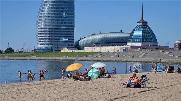 Strand in Bremerhaven mit Blick auf ein Hotel und das Klimahaus im Hintergrund. 
