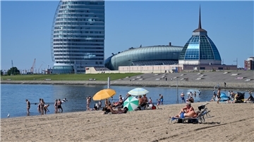 Strand in Bremerhaven mit Blick auf ein Hotel und das Klimahaus im Hintergrund. 