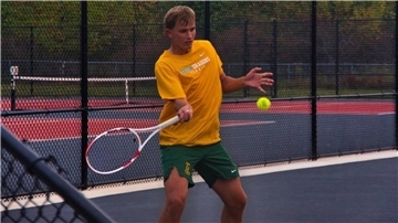 Ein Mann im orangefarbenen T-Shirt spielt Tennis.