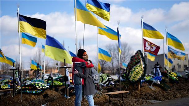 Trauernde umarmen sich während der Beerdigung einer Sanitäterin der ukrainischen Armee.