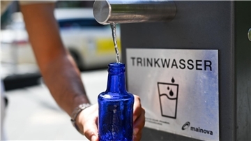 Aus einem Trinkwasserbrunnen wird Wasser in einen Behälter abgefüllt.