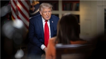 Donald Trump sitzt auf einem Stuhl und wird von einer Journalistin interviewt. 