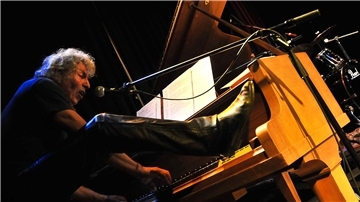 Ein älterer Mann spielt mit dem Fuß Klavier