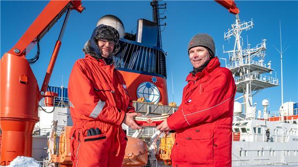 Übergabe in der Antarktis: Gerhard Frank (links), DGzRS-Ehrenamtlicher und Bordtechniker auf dem deutschen Forschungseisbrecher „Polarstern“, überreicht Peter Köhler, Expeditionsleiter der Neumayer-Station, ein Sammelschiffchen der Seenotretter auf Nord- und Ostsee.
