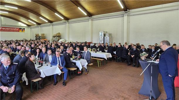 Landrat Thorsten Krüger spricht vor voll besetzten Tischen in der Fahrzeughalle der Feuerwehrtechnischen Zentrale Schiffdorf bei der Ehrung der Hochwasserhelfer.