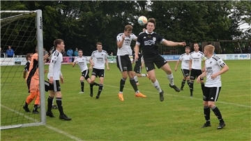 Zwei Männer springen zu einem Ball hoch und sechs Männer schauen zu.