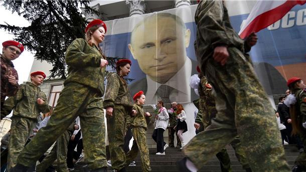 Putin überraschend auf annektierte Halbinsel Krim Uniformierte Jugendliche marschieren in Jalta anlässlich einer Aktion zum neunten Jahrestag der Krim-Annexion an einem Bild des russischen Präsidenten Wladimir Putin vorbei.