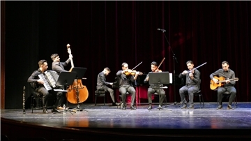 Mehrere Musiker spielen gemeinsam auf einer Bühne.