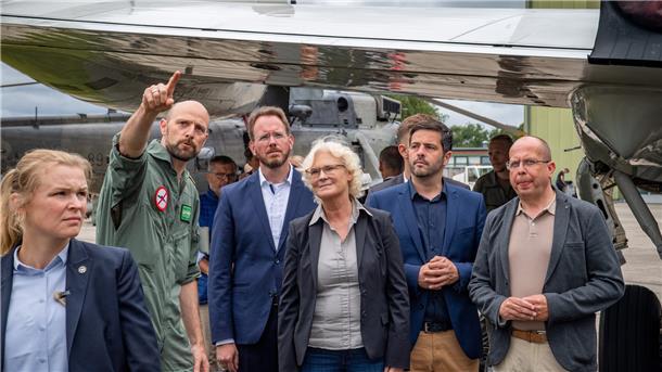 Unter dem wachen Blick einer Security-Mitarbeiterin (von links) erklärt ein Marineflieger Bürgermeister Marcus Itjen, Ministerin Lambrecht, dem SPD-Bundestagsabgeordneten Daniel Schneider und dem stellvertretenden Bürgermeister der Stadt Cuxhaven Oliver Ebken ein Waffensystem.