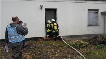 Unter den kritischen Augen der Übungsbeobachter betritt ein Angriffstrupp unter Atemschutz das Gebäude zur Menschenrettung.