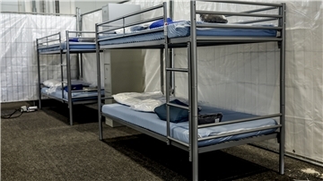 Das Foto zeigt eine Flüchtlingsunterkunft in einer Turnhalle. 