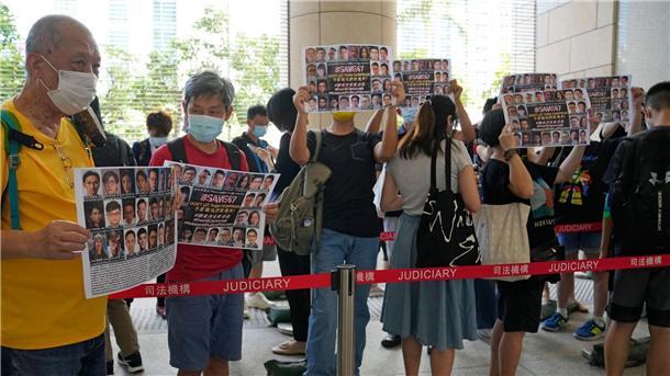 „Hongkong 47“: 14 Demokratie-Aktivisten schuldig gesprochen Unterstützer halten vor einem Gericht in Hongkong Plakate mit den Fotos einiger der 47 angeklagten Demokratie-Aktivisten in die Höhe.