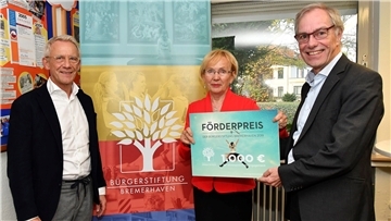 Uwe Perl (links) und Christian Bruns (rechts) überreichten Gisela Wiegel den Förderpreis der Bürgerstiftung Bremerhaven für ihr ehrenamtliches Engagement.